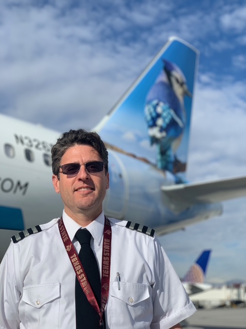 Clint Powell, owner and founder of Eagle Aviation, in captain's uniform on the airport ramp