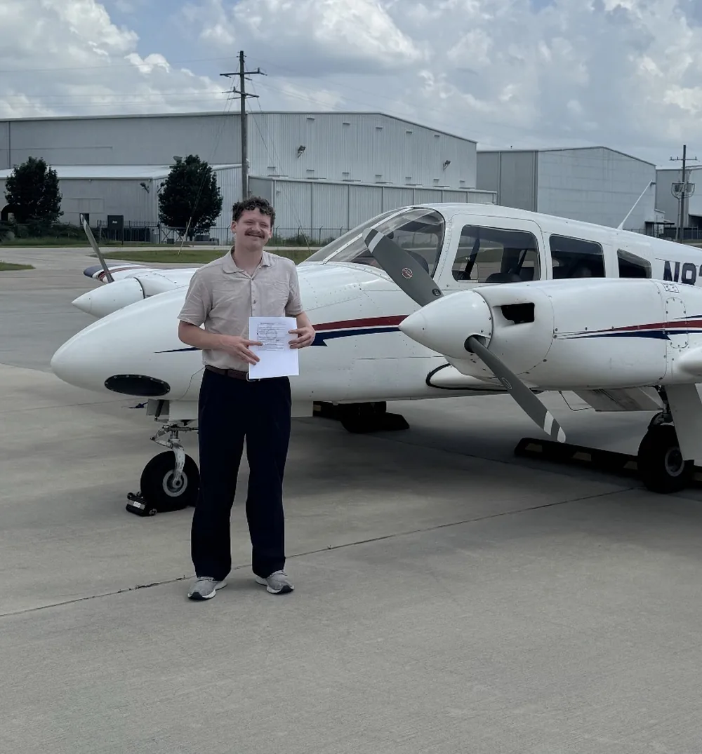 Payton, certified flight instructor at Eagle Aviation, on the ramp beside a twin-engine training aircraft